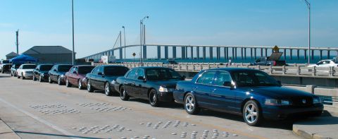 1997 Ford Crown Victoria - A line of Ford Crown Victoria police interceptors and similar sedans are parked on a bridge.