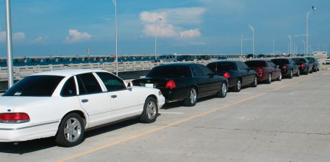 1997 Ford Crown Victoria - A line of Ford Crown Victorias are parked on a sunny day with a bridge in the background.
