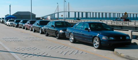 1997 Ford Crown Victoria - A line of Ford Crown Victoria sedans, including police interceptor models, are parked on a bridge.