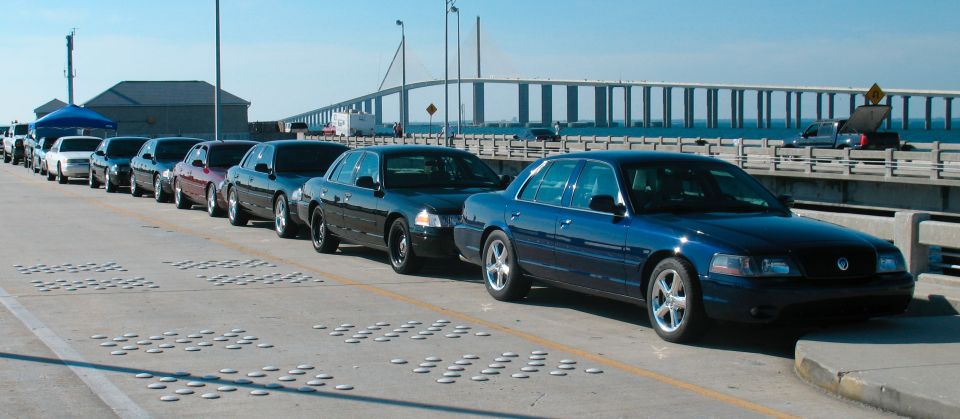 Blue Ford Crown Victoria in a line of similar cars on a bridge