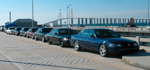 1997 Ford Crown Victoria - Multiple Ford Crown Victoria models, including police interceptors, parked in a line on a bridge.