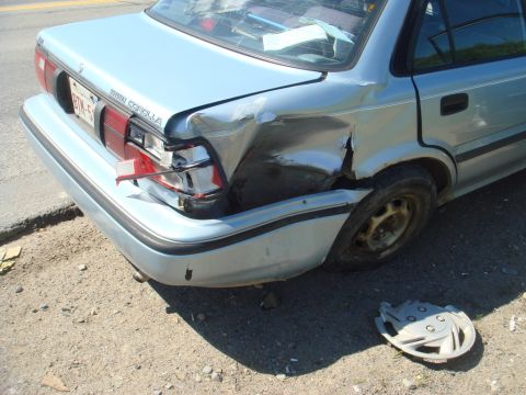 1996 Ford Bronco - This light blue sedan has sustained severe damage to its rear quarter panel and taillight, with the 'TOYOTA COROLLA' badging still visible.