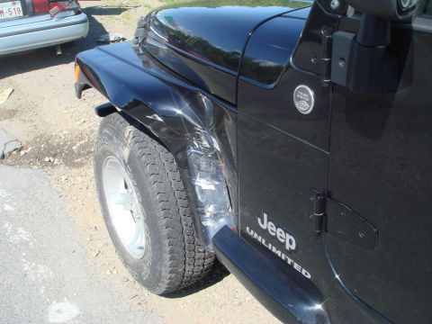 1996 Ford Bronco - A black Jeep Wrangler shows significant damage to its front fender and door panel.