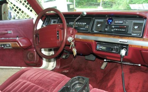 1991 Ford LTD Crown Victoria - Red interior of a 1990s Ford full-size sedan: leather-wrapped wheel, digital dash readout, aftermarket stereo and a CB mic.