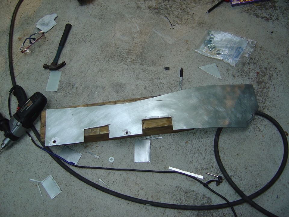 Metal sheet being cut and shaped with tools on a concrete floor