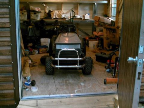 1986 Ford Bronco - A riding mower sits in a garage filled with storage and tools.