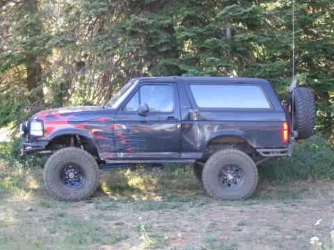 1979 Ford Bronco - Modified Ford Bronco with flame decals and off-road tires parked outdoors.