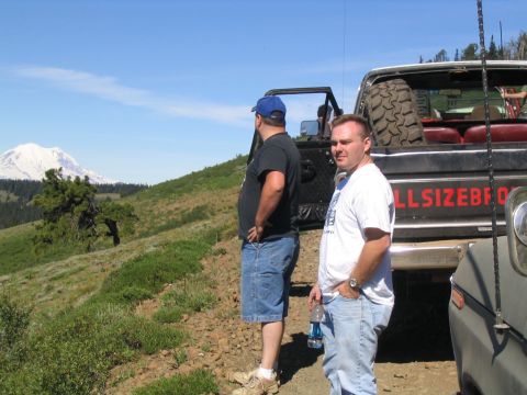 1979 Ford Bronco - Two men stand beside a 1979 Ford Bronco and another off-road vehicle, with a mountain visible in the distance.