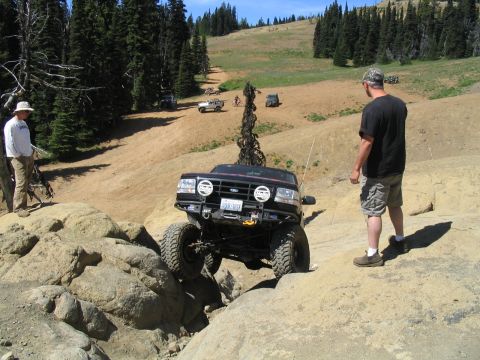 1979 Ford Bronco - Off-road vehicle tackling a challenging rocky obstacle on a sunny day.