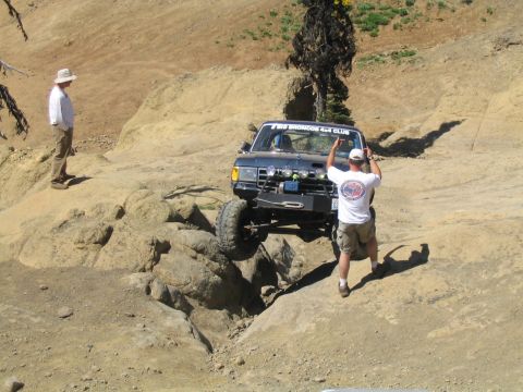 1979 Ford Bronco - A Ford Bronco navigates a rocky trail, with a spectator observing the challenging terrain.