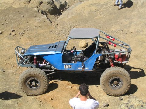 1979 Ford Bronco - A custom blue off-road buggy with a prominent roll cage and fire extinguishers is seen in a rocky, off-road environment.