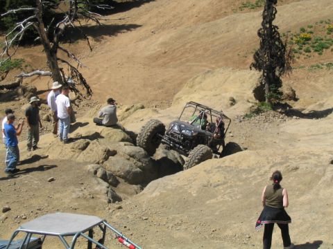 1979 Ford Bronco - A group watches an off-road vehicle navigate a challenging rocky terrain on a sunny day.