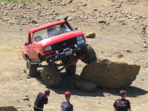 1979 Ford Bronco - A red pickup truck navigates a rocky obstacle course, demonstrating its off-road capabilities.