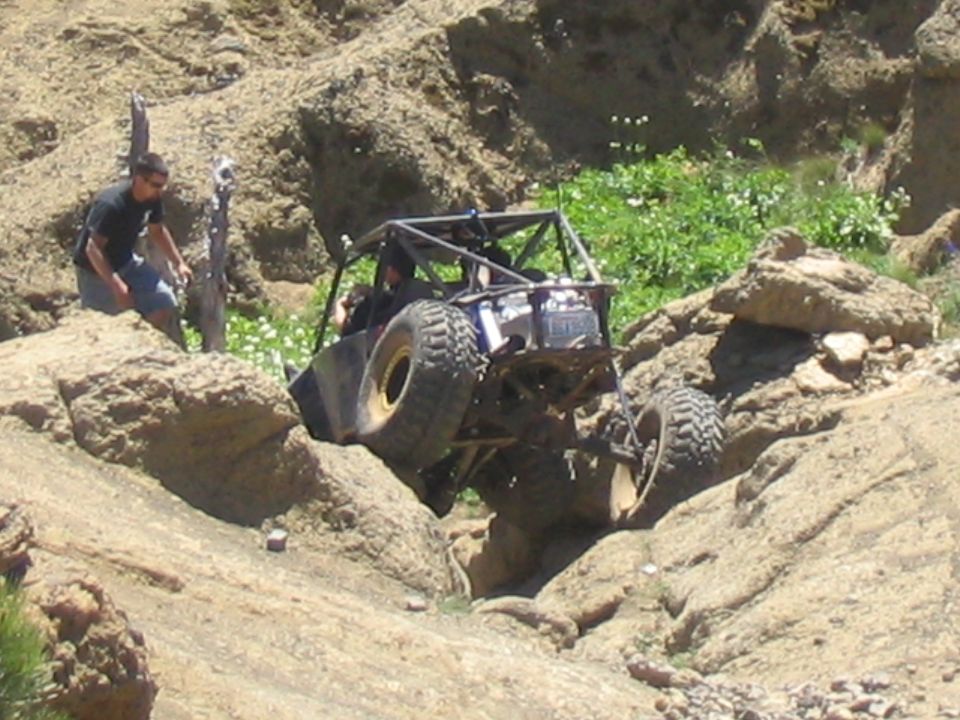 Off-road buggy with roll cage navigating rocky terrain