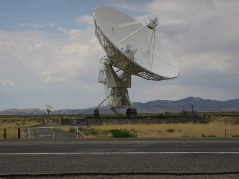 1999 Ford F-250 - A large radio telescope dish dominates the landscape, with a smaller dish visible in the distance under a cloudy sky.