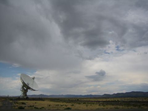 1999 Ford F-250 - A large radio telescope stands in a vast, dry landscape beneath a dramatic, cloudy sky.