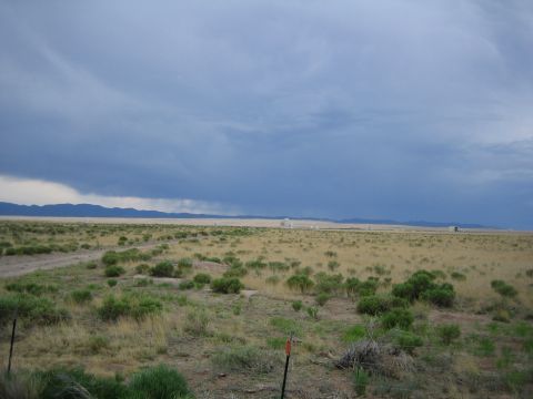1999 Ford F-250 - A lone truck is visible in the distance across a wide, arid plain with scattered brush and mountains on the horizon.