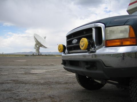 1999 Ford F-250 - Front view of a 1999 Ford F-250 pickup truck, equipped with yellow smiley face fog lights, parked near a large satellite dish.