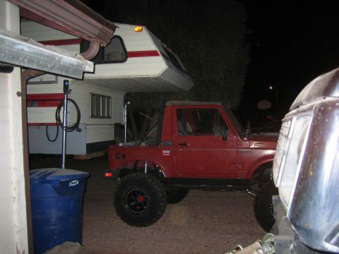1987 Suzuki Samurai - Side view of a lifted red 1987 Suzuki Samurai with aftermarket wheels and tires.
