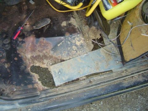 1979 Ford Bronco - The interior floor pan shows significant rust and damage, with tools and a container visible.