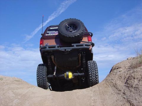 1986 Ford Bronco II - This SUV is equipped with off-road tires and a custom rear bumper, navigating a steep dirt incline.