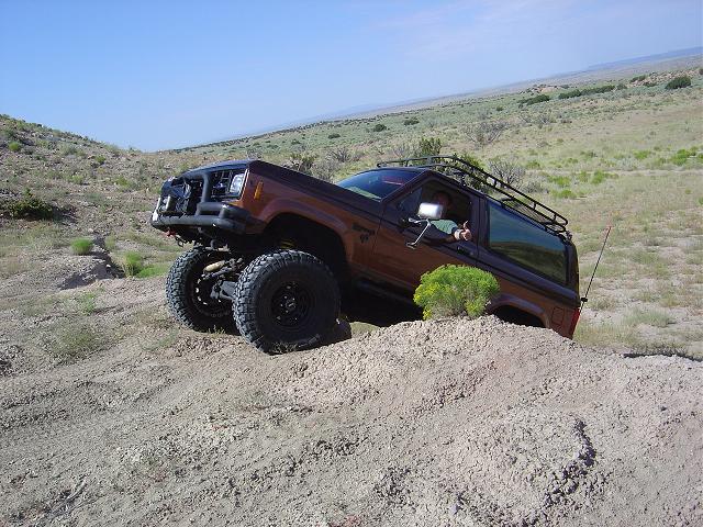 Brown SUV with roof rack on a dirt hill, lifted suspension, off-road tires