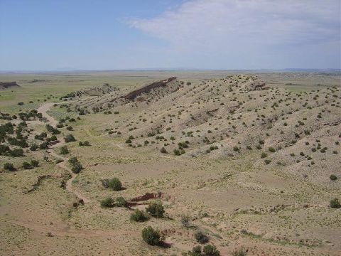 1986 Ford Bronco II - A wide view of a dry, arid landscape under a clear blue sky, rolling hills and a distant mesa.