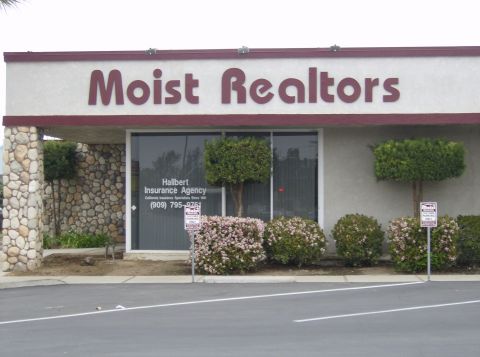 1986 Ford Bronco - Exterior of a commercial building with signage for 'Moist Realtors' and 'Hallbert Insurance Agency'.