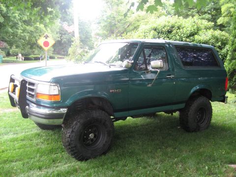 1996 Ford Bronco - This lifted 1996 Ford Bronco is parked on a grassy lawn with trees in the background.