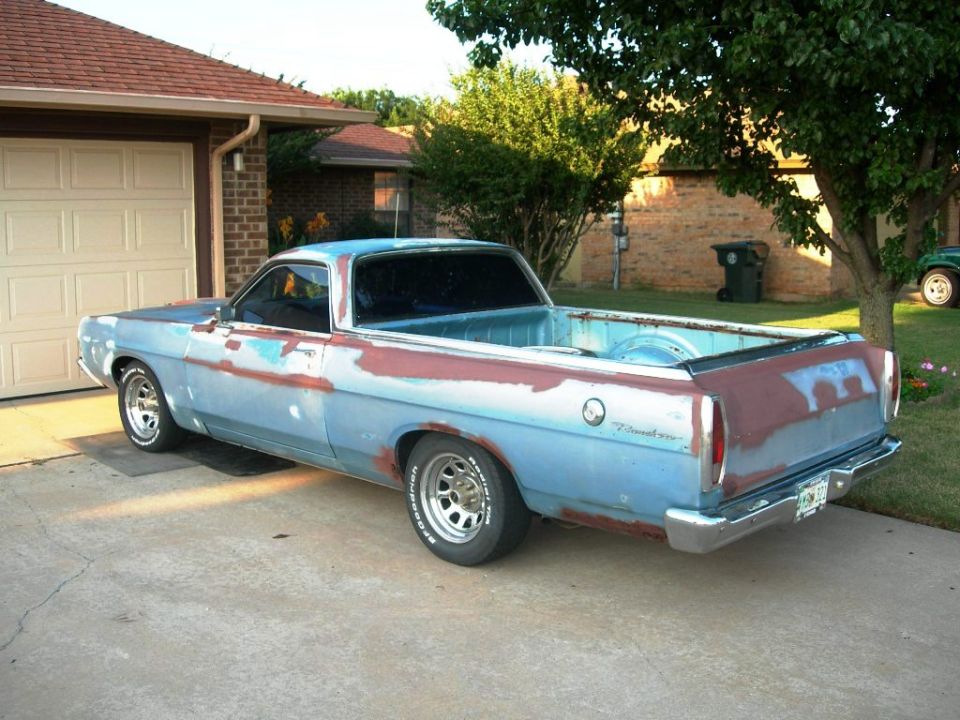 Rear 3/4 view of a faded blue and rust Ford Ranchero pickup in a driveway
