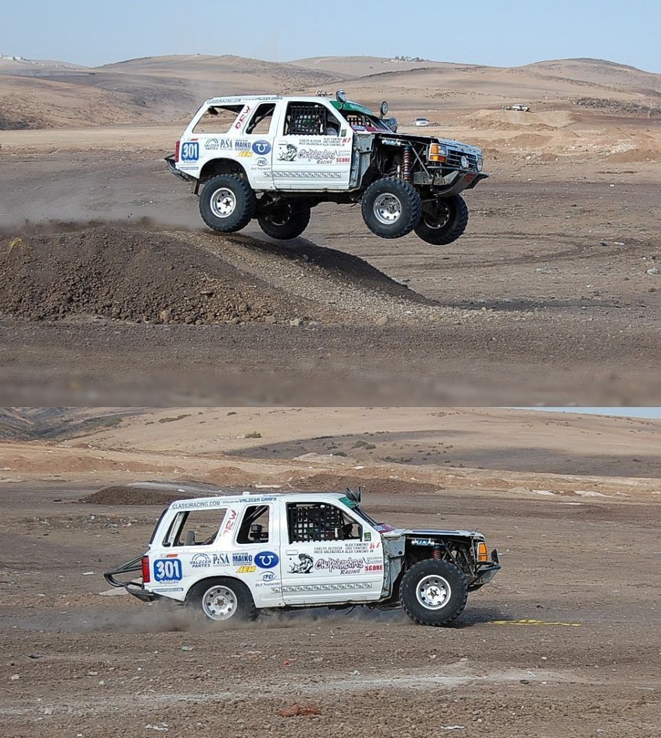 White off-road SUV with number 301 on door, mid-air over dirt mound. Front end is stripped down