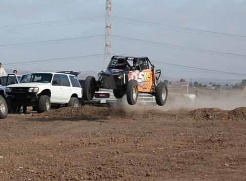 1992 Ford Explorer - An off-road buggy is airborne during a race, with other vehicles and spectators in the background.