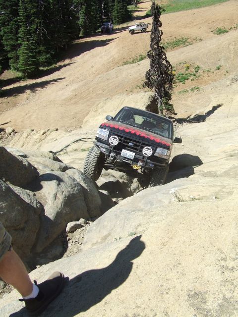 1979 Ford Bronco - This modified SUV is tackling a challenging rocky trail, with other vehicles in the background.