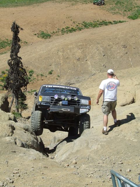 1979 Ford Bronco - A black 1979 Ford Bronco tackles a challenging rocky trail, with a man watching and another ATV visible in the background.
