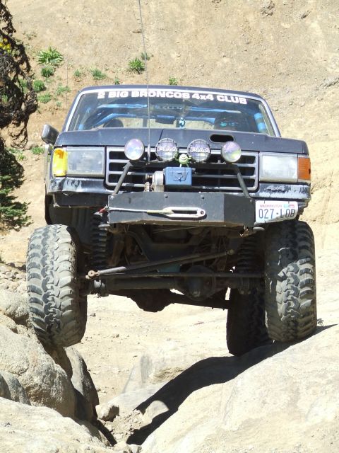 1979 Ford Bronco - This modified truck is navigating a rocky off-road trail, displaying a club sticker and license plate.