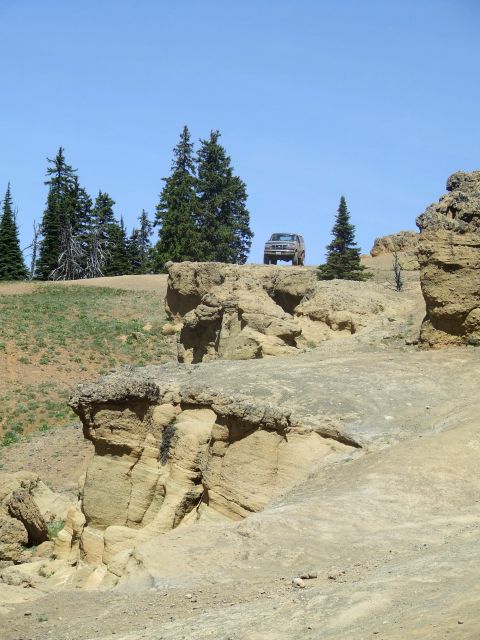 1979 Ford Bronco - A lone SUV navigates a , rocky landscape under a bright blue sky.