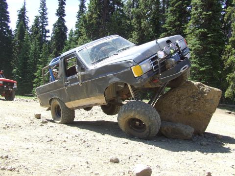 1979 Ford Bronco - This dark gray SUV is navigating a rocky trail, with a red SUV in the background.