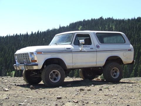 1979 Ford Bronco - A lifted 1978 Ford Bronco with off-road tires sits on a rocky surface with a forest in the background.