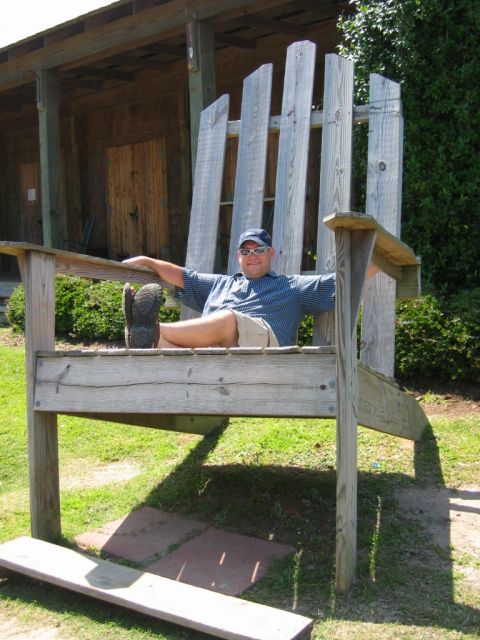 1985 Ford LTD Crown Victoria - A man relaxes in an oversized Adirondack chair on a sunny day.