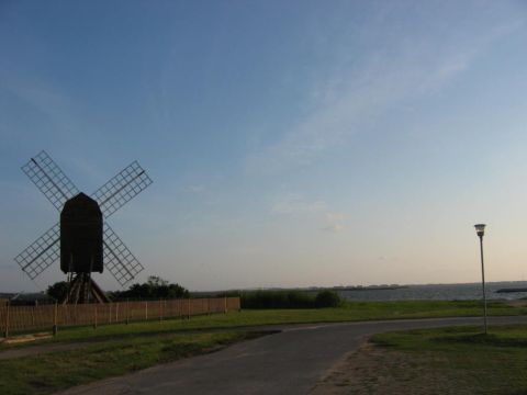 1985 Ford LTD Crown Victoria - A scenic view of a windmill by the water under a clear sky.