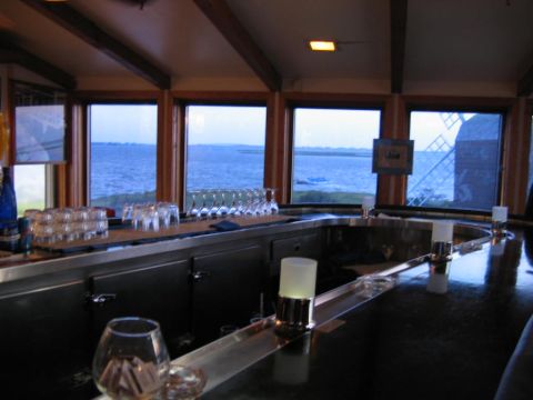 1985 Ford LTD Crown Victoria - A bar scene with glassware on the counter and a scenic view of the water outside.