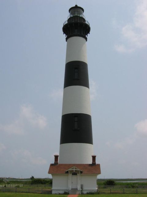1985 Ford LTD Crown Victoria - A tall lighthouse with black and white bands stands against a partly cloudy sky.