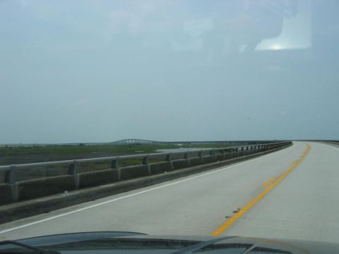 1985 Ford LTD Crown Victoria - View from the driver's seat as the car travels across a long bridge spanning a marshy coastal area.