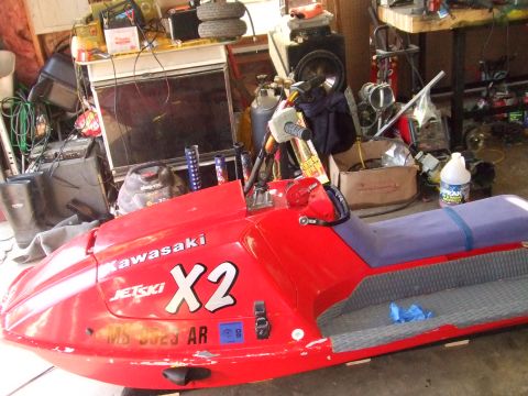 1998 Kawasaki JH1100-A4 1100 ZXi - A red Kawasaki X2 jet ski is parked in a cluttered garage, showing its registration number MS 3023 AR.