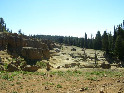 1989 Ford Bronco - Multiple ATVs navigate a , rocky terrain under a clear blue sky.