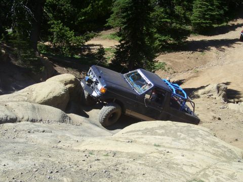 1989 Ford Bronco - A modified truck navigates a rocky trail, with another vehicle visible further up the path.