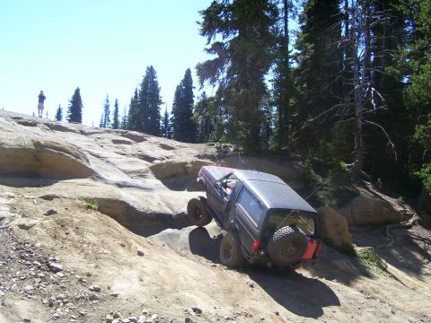 1989 Ford Bronco - A 1989 Ford Bronco navigates a challenging off-road course on a sunny day.