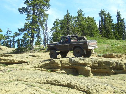 1989 Ford Bronco - This black 1978 Ford Bronco navigates a , rocky landscape under a clear blue sky.