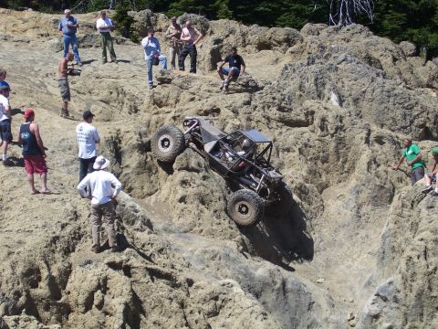 1989 Ford Bronco - A custom-built buggy attempts to climb a challenging rocky terrain, with onlookers observing the action.