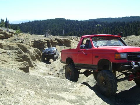 1989 Ford Bronco - A red 1989 Ford Bronco navigates a off-road course with another vehicle behind it.